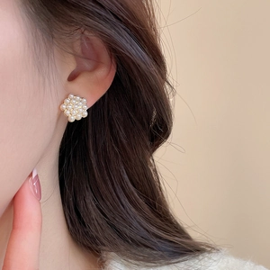 Detailed view of elegant flower-shaped pearl earrings on model in warm beige setting