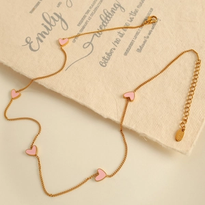 Elegant gold necklace with five pink heart pendants on textured paper background