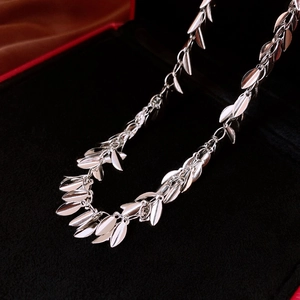 Detailed view of silver sequin wheat leaf fringe necklace on black velvet display case