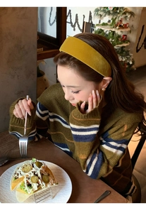 Detail of mustard yellow plush wide headband shown on model in a cozy vintage setting