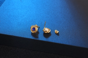 Detailed macro view of gold titanium earrings featuring blue zircon and spiral design