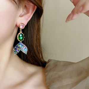 Gros plan de boucles d'oreilles queue de poisson vintage avec gemmes colorées