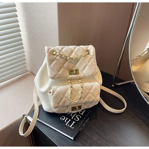 Detail of white quilted backpack featuring metal twist locks and classic chain straps