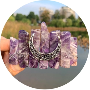 Bohemian purple crystal moon hair clip held by hand with a scenic lake background