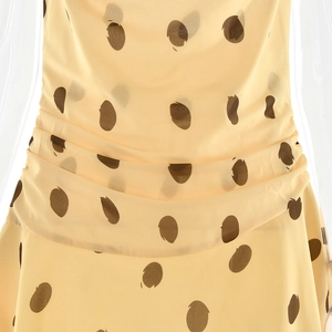 Close-up of yellow chiffon polka dot dress featuring detailed waist pleats and soft texture