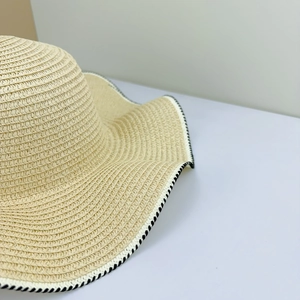 Detail of beige woven sun hat brim featuring black and white stitched edge lock