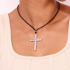 Macro shot of 18K gold plated zircon cross pendant with simple black rope on neck