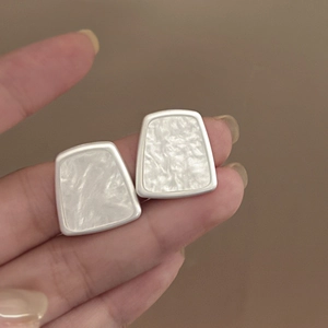 Detail showing trapezoid silver geometric earrings with white marble resin inlay texture