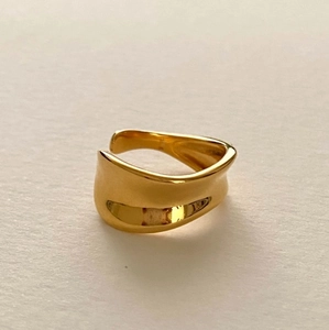 Macro shot of minimalist polished gold open ring with irregular liquid wave texture