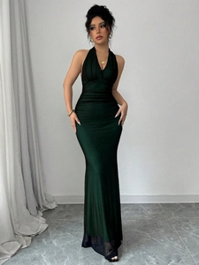 Close-up of the emerald green backless halter dress with ruching details and fishtail hem