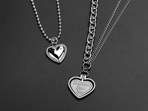 Detail of silver titanium steel necklaces featuring heart pendants and engraved text