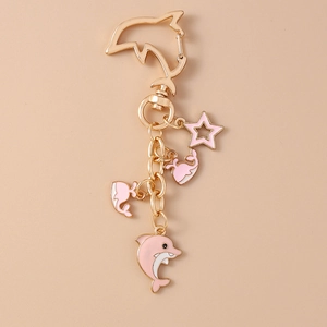 Detailed view of pink dolphin keychain with gold metal plating and enamel charms