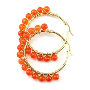 Detailed macro of gold wire wrapped hoop earrings with orange carnelian stone beads