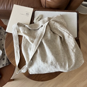 Detailed texture of natural beige linen tote bag with wide strap on a wooden table