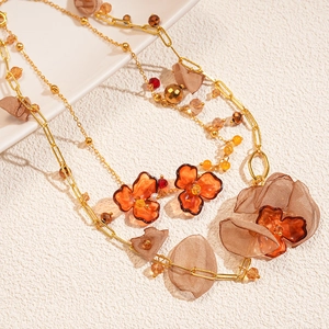 Close-up of amber acrylic flower necklace with beige chiffon petals and gold chain links
