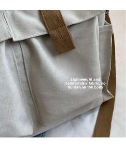 Close-up of high-density canvas texture and utility pocket detail on beige crossbody bag