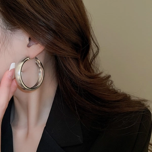 Close-up of a silver oversized hoop earring worn by a model in black blazer