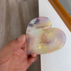 Close-up of heart-shaped claw clip in iridescent purple and yellow pearlescent finish