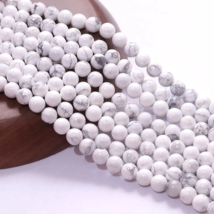 Natural white turquoise round beads with grey marble veins on dark wood display tray