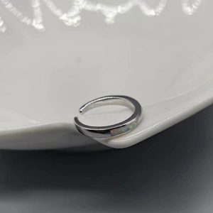 Close-up of S925 sterling silver opal toe ring on a white ceramic plate edge