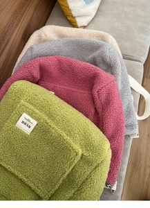Detailed texture of stacked lamb wool tote bags in green, pink, grey and off-white colors