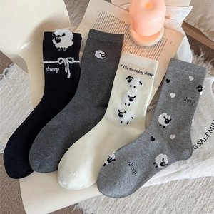 Detail view of four cotton socks in neutral tones with sheep patterns and embroidery