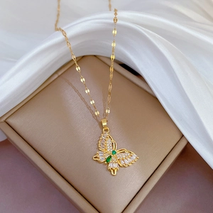 Macro shot of gold butterfly pendant with green gems and diamonds on silk in box