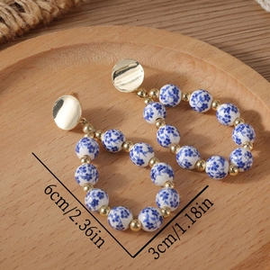 Blue and white porcelain bead earrings with gold accents on a wooden tray