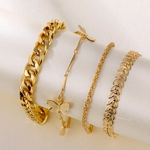 Dettaglio di un set di 4 braccialetti dorati con farfalla e catena cubana su supporto