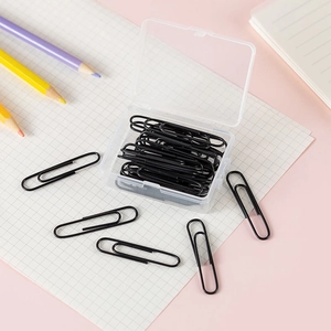 Close-up of black metal paperclips in a transparent storage box on a desk