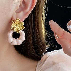 Gros plan détaillé de boucles d'oreilles fleur vintage avec pétales dorés et cercles roses