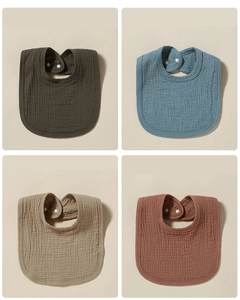 Collage of four soft gauze baby bibs in olive green, dusty blue, khaki, and rust red tones