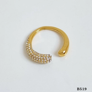Detail of gold-plated open ring with white crystals on a clean beige surface