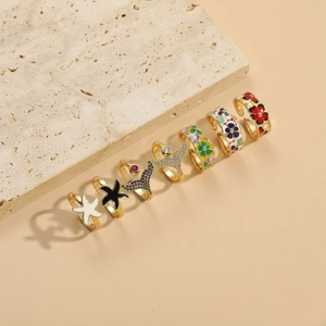 Détail de bagues dorées avec étoiles de mer en émail coloré et motifs de queue de poisson