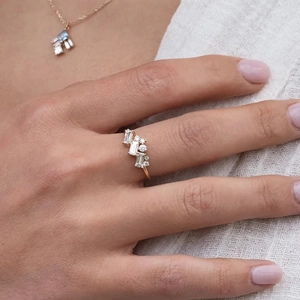 Close-up of cluster diamond ring and gold necklace set on model with luxury sparkle