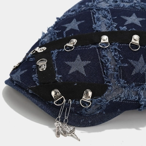 Detail of blue denim beret with frayed star pattern, black ribbon and metal charms