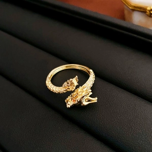 Detail of gold dragon ring with sparkling clear zircons and red eyes on black leather