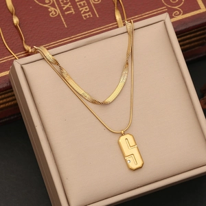 Close-up of double-layer gold necklace with geometric pendant and small crystal