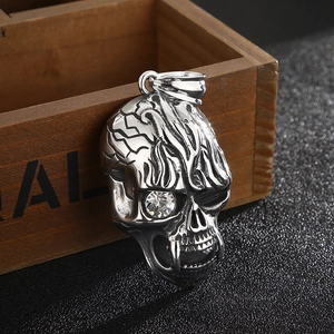 Detailed macro view of a silver skull pendant with clear gemstone and textured metal face