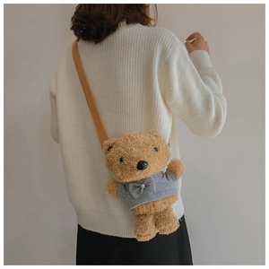 Detail of plush brown bear crossbody bag with grey sweater and pearl bow decoration