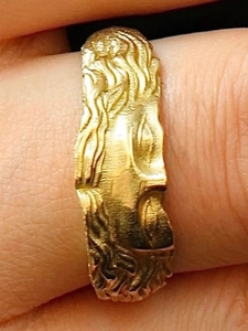 Macro shot of gold irregular wave ring with brushed texture on finger