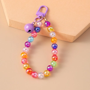 Macro shot of colorful iridescent beads with a purple bell and clasp on beige stand