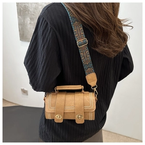 Detail of retro cylinder shoulder bag with ethnic embroidered strap and faux leather texture