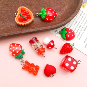 Flat lay of red resin charms including strawberry, heart and mushroom for DIY jewelry making