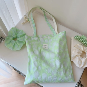 Close-up of mint green jacquard floral tote bag with matching scrunchies and hair clips