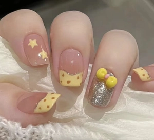 Detail of handmade yellow French press-on nails with bow, stars, and glitter accents