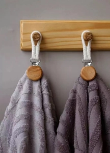 Close-up of woven cotton rope towel clips with wood accents holding purple fabric