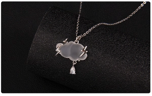Close-up of frosted cloud pendant with silver lightning charms and a pear-shaped gemstone