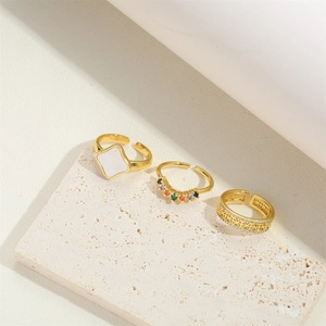 Three gold adjustable rings featuring white shell, colorful gems and cutout crystal pavé