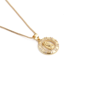 Detailed close-up of a gold-plated necklace featuring a Virgin Mary pendant with crystals